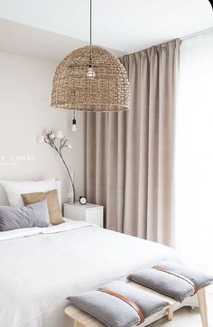 a bedroom with a bed, two pillows and a wicker light fixture