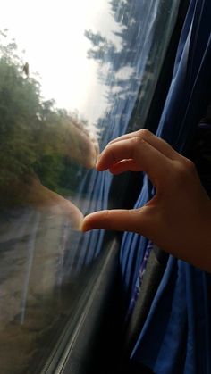 a person's hand reaching out the window of a vehicle with trees in the background