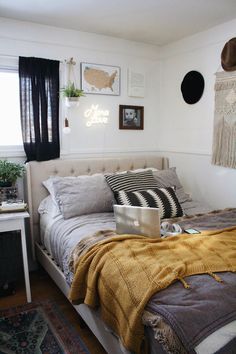 a bed room with a neatly made bed and a laptop on the end table next to it