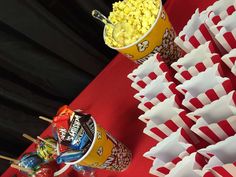 popcorn buckets and candy sticks on a table with red and white striped paper cups