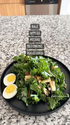 a black plate topped with lettuce and hard boiled eggs on top of a counter