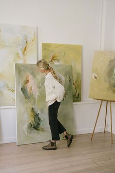 a woman standing in front of some paintings