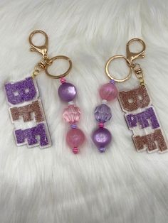 three keychains with different designs on them sitting on a white furnishing