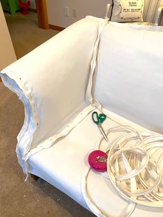 an upholstered white couch with scissors and thread on the back end, sitting in a living room