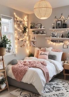 a bedroom with lights strung above the bed, and a pink blanket on the bed