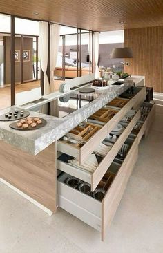 an open kitchen with lots of drawers and plates on the counter top in front of it