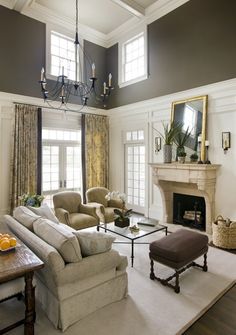 a living room filled with furniture and a fire place in front of a mirror on the wall