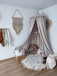 a baby's room is decorated in neutral colors and features a canopy bed, crib, stuffed animal toys, and wall hangings