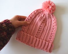 a hand holding a pink knitted hat