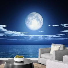 a living room with a view of the ocean at night and full moon in the sky