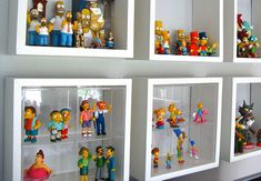 the simpsons figurines are on display in glass cases with white walls behind them