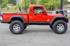 a red jeep is parked in a parking lot