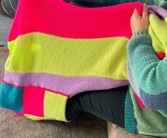 a woman is sitting on the floor holding a colorful blanket