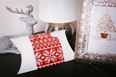 a white and red pillow sitting on top of a table next to a lamp