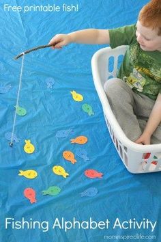 a young boy is sitting in a laundry basket and playing with magnets on the floor