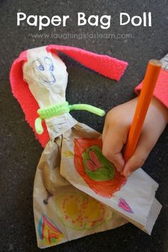 a child's hand writing on paper bag doll