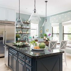 a large kitchen island with lots of counter space and hanging lights in the middle of it