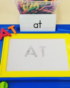 a plastic tray with letters and magnets on it next to a container filled with colored paper clips