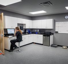 a woman sitting at a desk with a computer on it in an office cubicle