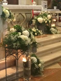 flowers and candles are lined up on the steps in front of a church pews