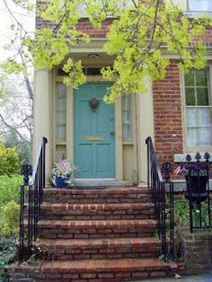 a blue door is on the front steps of a brick house with wrought iron railings