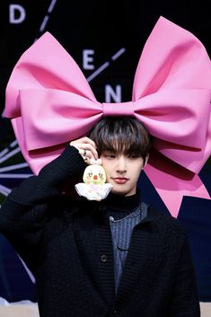 a man with a big pink bow on his head holding a stuffed animal in front of his face