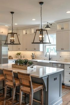 a kitchen with an island and chairs in the center, lights hanging from the ceiling