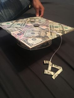 a graduation cap made out of money sitting on top of a black cloth covered table