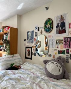 there is a bed with many pictures on the wall and a teddy bear laying on it