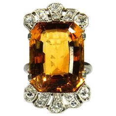 Art Deco 18.7 Carat Citrine Diamond Cocktail Ring in 18K White Gold, circa 1930 Elegant cocktail ring with a lattice-shaped openwork ring head, set with a magnificent cognac-colored 18.7 carat citrine, crowned by diamonds totaling 0.5 carat 18K white gold 1 citrine approx. 18.7 ct carat in emerald cut, 18.53 x 14.25 mm 16 brilliant-cut diamonds, total approx. 0.50 ct, G-H / Si-P Ring head size 29.84 x 17.03 mm Ring size 53 Weight 10.39 g stamped 750 very good condition Supplied with an Independe Art Deco Topaz Ring With Center Stone, Vintage Octagon Ring With Center Stone, Vintage Rings With Octagon Center Stone, Antique Orange Rings For Formal Occasion, Vintage Orange Rings For Formal Occasions, Orange Vintage Rings For Formal Occasions, Art Deco Octagon Ring For Formal Occasions, Vintage Octagon Gemstone Ring, Formal Art Deco Octagon Ring