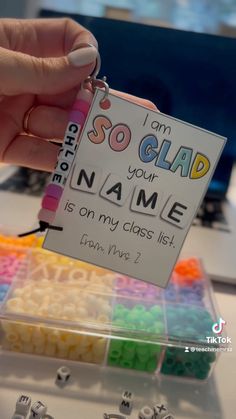 a person is holding a name tag in front of some beads and magnets on a table