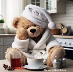 a teddy bear wrapped in a towel sitting next to a cup of tea