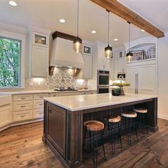 a large kitchen with an island in the middle of it and three stools at the end