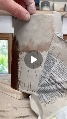 a person is making a sculpture out of newspaper and wood with their thumb on it