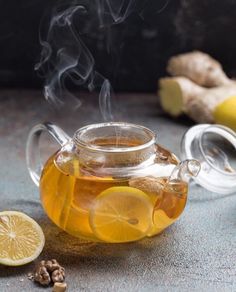 a glass tea pot filled with liquid and lemon slices