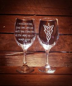 two wine glasses sitting on top of a wooden table with words written in white ink