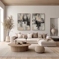 a living room with two paintings on the wall and furniture in front of an open floor plan