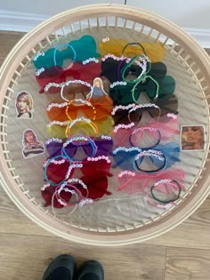 a basket filled with lots of different colored sunglasses on top of a wooden floor next to a pair of black shoes