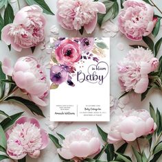 pink peonies and greenery surround the baby announcement card on a white background