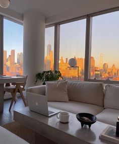 a living room filled with furniture next to large windows and a view of the city