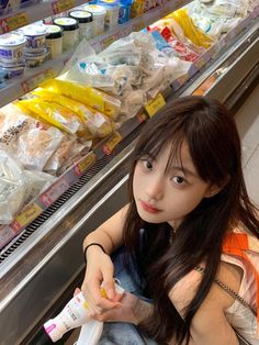 a woman sitting on the ground in front of a display case filled with milk and yogurt