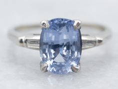 an oval cut blue topazte ring with two white gold accents on the band