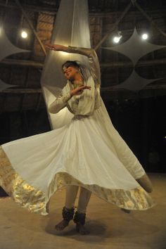 a woman is dancing in a white dress