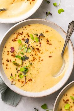 two bowls filled with soup and garnished with sprouts on the side