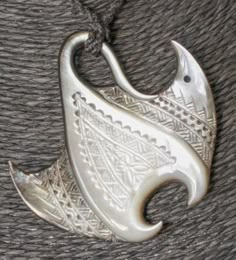 a silver pendant with an intricate design on it's end and a fish in the middle