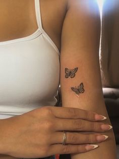 a woman's arm with two small butterflies on the left side of her arm