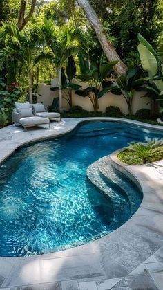 an outdoor swimming pool surrounded by greenery and trees, with lounge chairs on the side