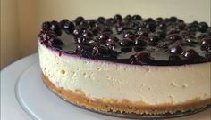 a cheesecake with blueberries on top is sitting on a white cake platter