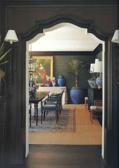 an open doorway leading to a dining room with blue vases on the table and chairs