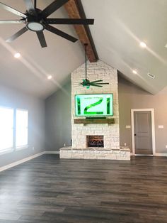 an empty living room with a ceiling fan and tv mounted on the wall above it